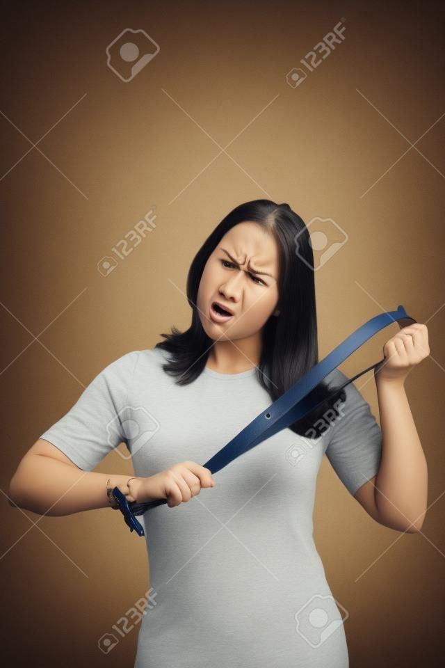 Angry young mother with belt on her hands