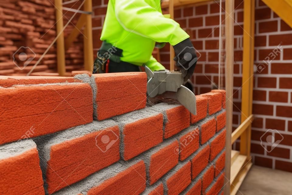 Trabajador de construcción de mampostería pared de la casa con ladrillos