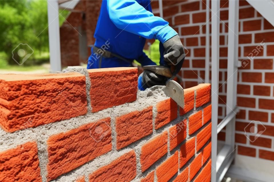 Worker building masonry house wall with bricks