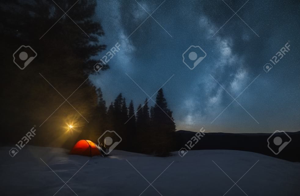 Night camping. Man and woman friends resting near night bonfire during mountaineering vacations for visiting Ukrainian nature environment, boyfriend and girlfriend have wild journey for trekking