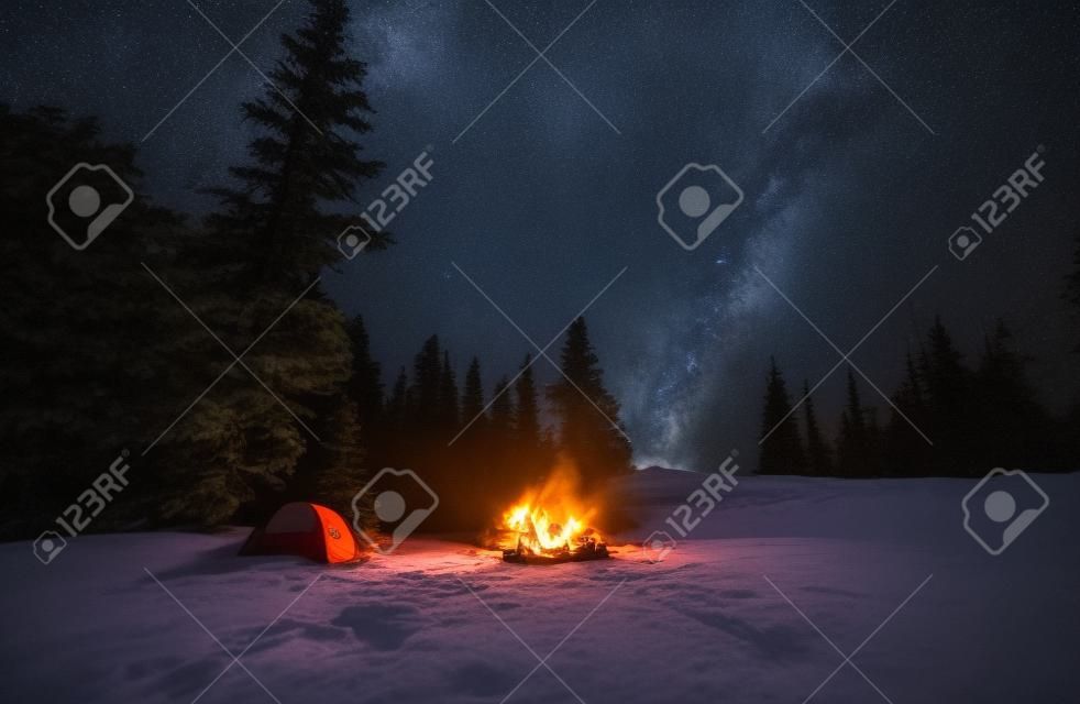 Night camping. Man and woman friends resting near night bonfire during mountaineering vacations for visiting Ukrainian nature environment, boyfriend and girlfriend have wild journey for trekking