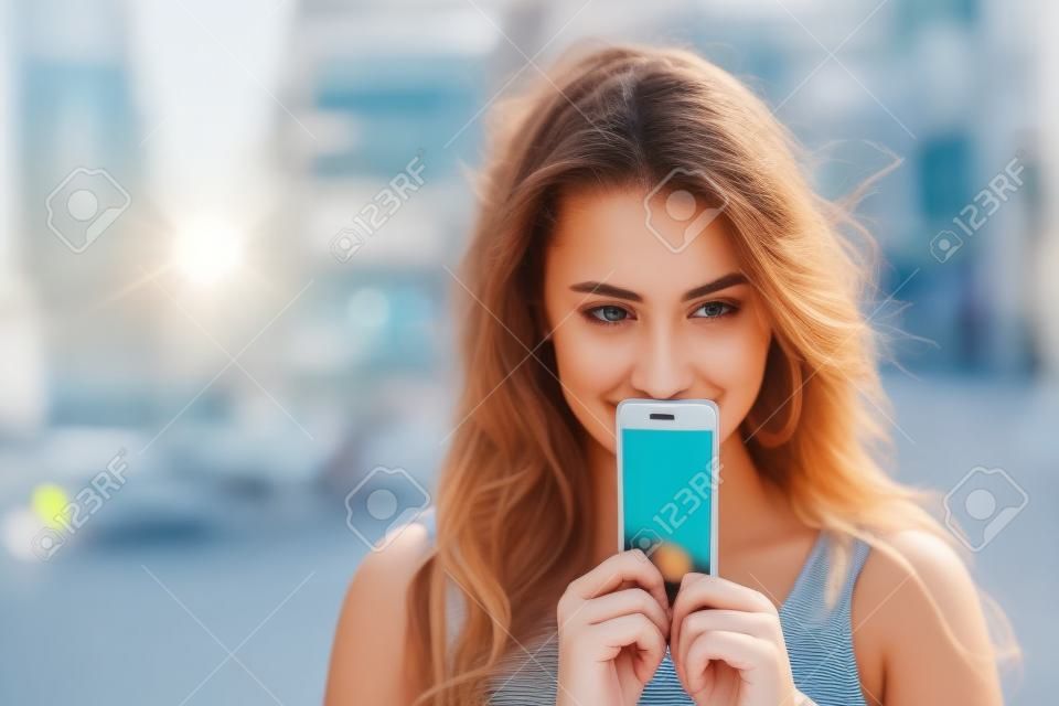 Genç kadın, bir arka plan yaz sokakta yüzü ekran smartphone kapakları