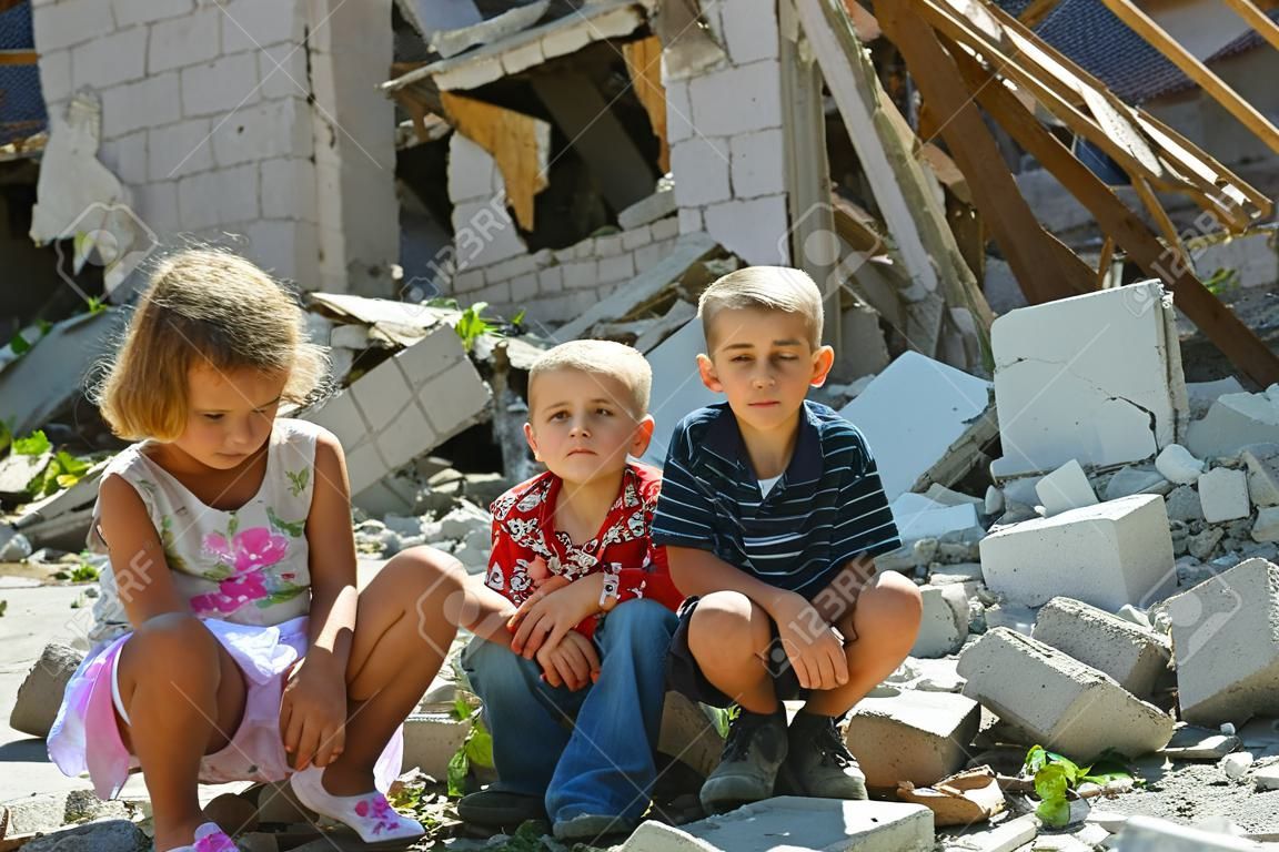 lLittle orphans were left without housing and stand near the ruins of the building as a result of a military conflict, a fire and an earthquake. Photo production.