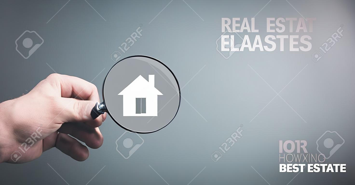 Man holding magnifier with house icon. Real estate