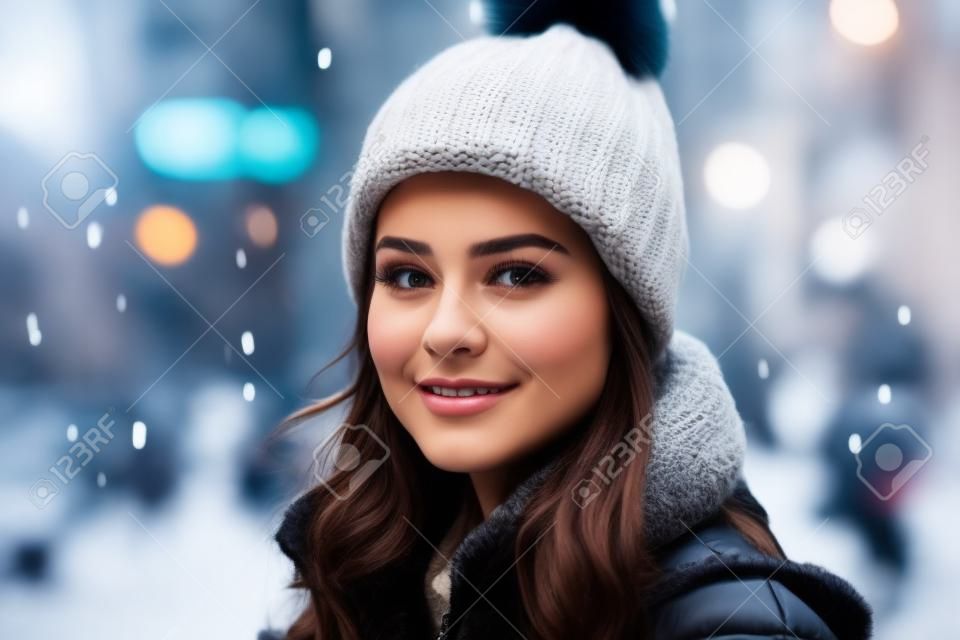 Beautiful young woman in a warm hat and coat walking in the city.