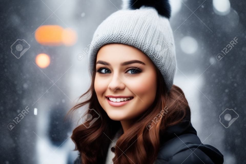 Beautiful young woman in a warm hat and coat walking in the city.