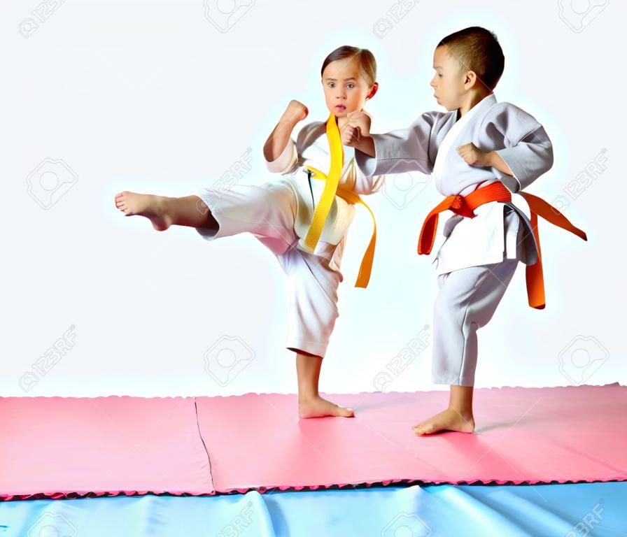 Girl and boy in karategi are beating kick leg forward