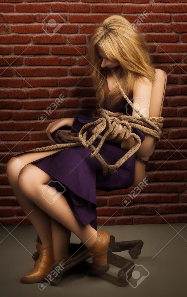 Frau gefesselt mit einem Seil gegen die Wand