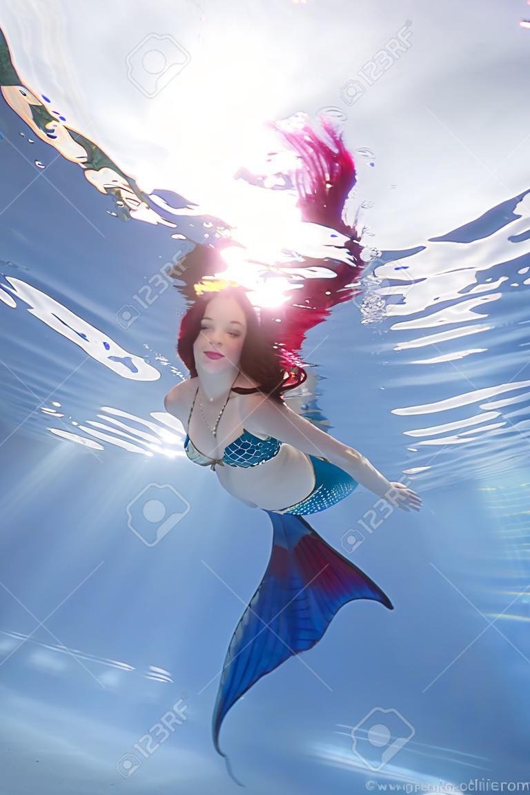 Dziewczyna w stroju syreny pozuje pod wodą w basenie
