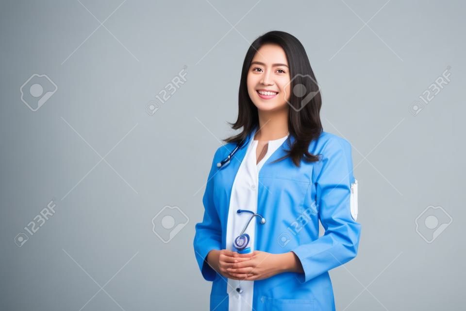 흰색 코트에 청진기를 들고 허리를 위로 한 아시아의 아름다운 여성 의사의 의료 개념. 의대생. 여성 병원 직원이 카메라를 보고 웃고, 스튜디오, 파란색 배경