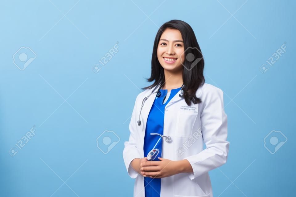 Conceito médico do médico feminino bonito asiático no revestimento branco com estetoscópio, cintura para cima. Estudante de medicina. Trabalhador do hospital da mulher que olha a câmera e o sorriso, estúdio, fundo azul