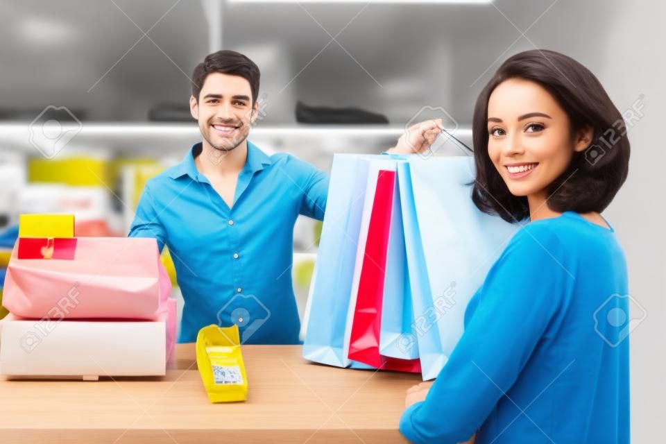Happy Male Cashier Handing Over Shopping Bag To Customer