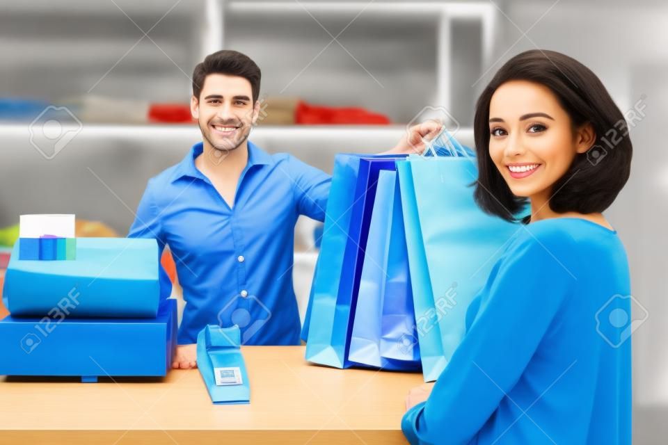 Caixa masculino feliz entregando sobre saco de compras para o cliente