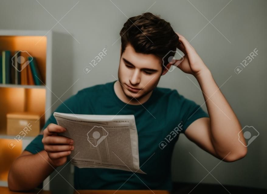 Contemplated Young Man Reading Paper Holding In Hands