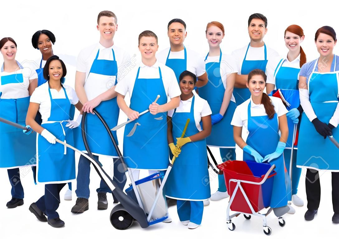 Large diverse group of janitors wearing blue aprons standing grouped together with their equipment smiling at the camera  isolated on white