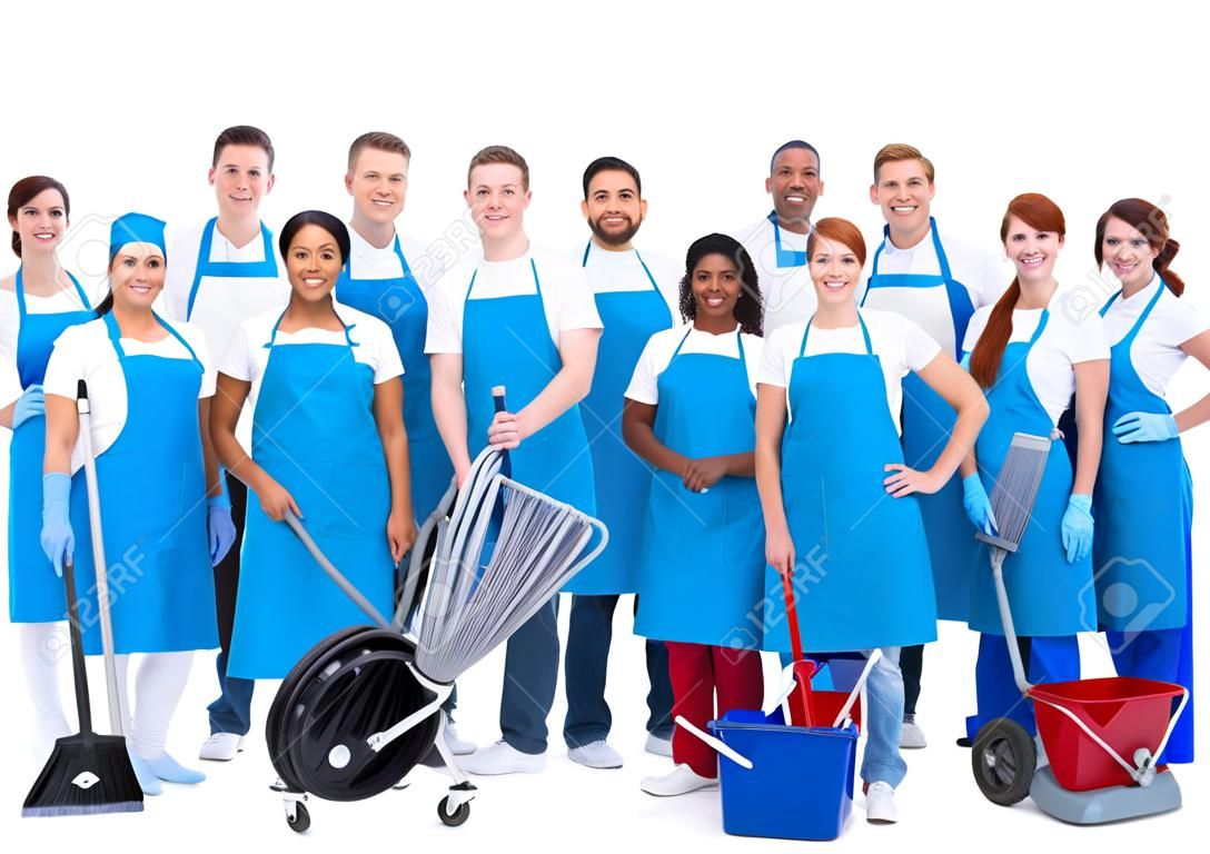 Numeroso grupo diverso de trabajadores de limpieza que usan azules delantales de pie agrupados junto con su equipo sonriendo a la cámara aislada en blanco