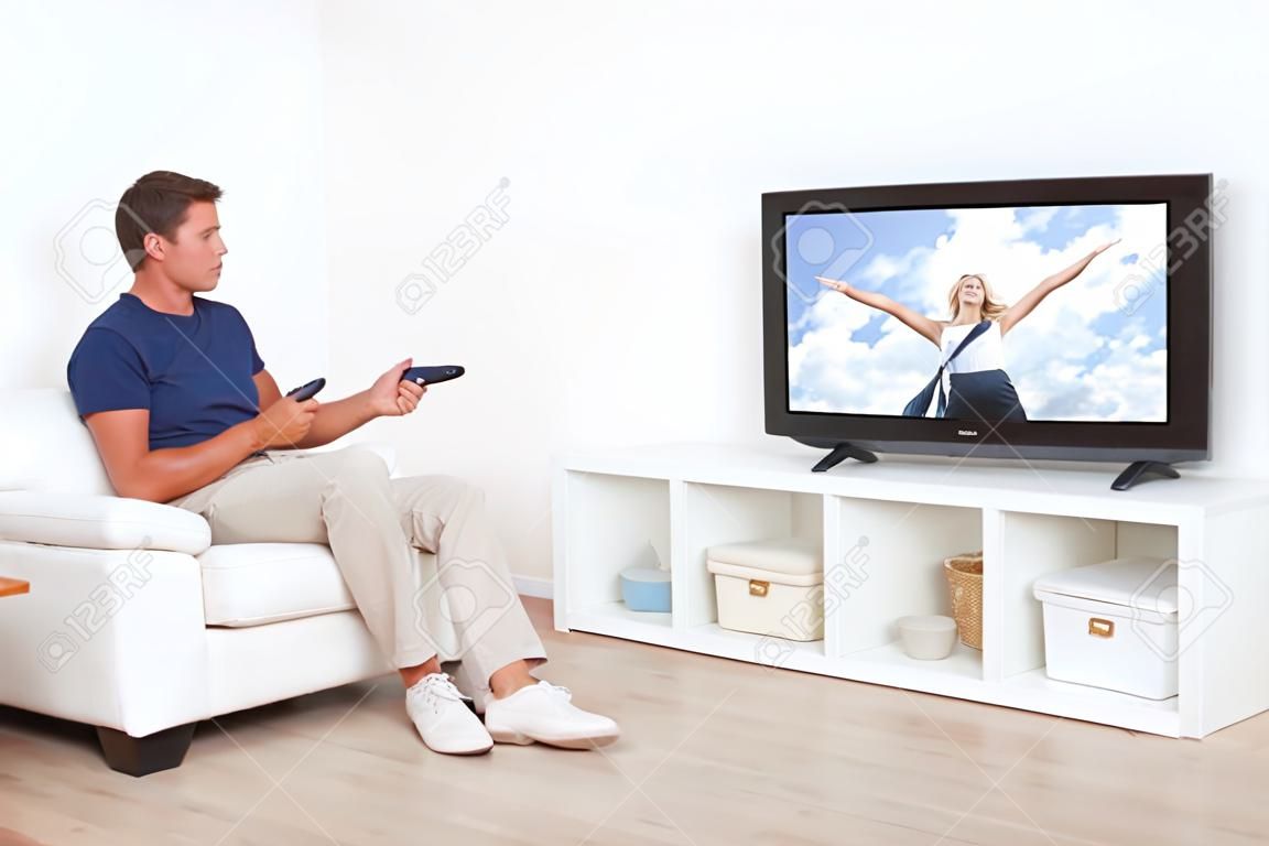 Pełna długość człowieka oglądania telewizji w salonie w domu