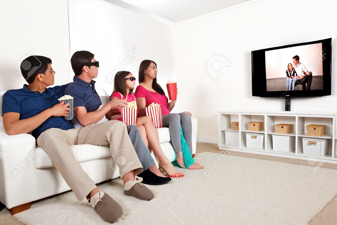 Longitud total de la familia viendo la película en 3D en la televisión, mientras que comer rosetas de maíz en el país