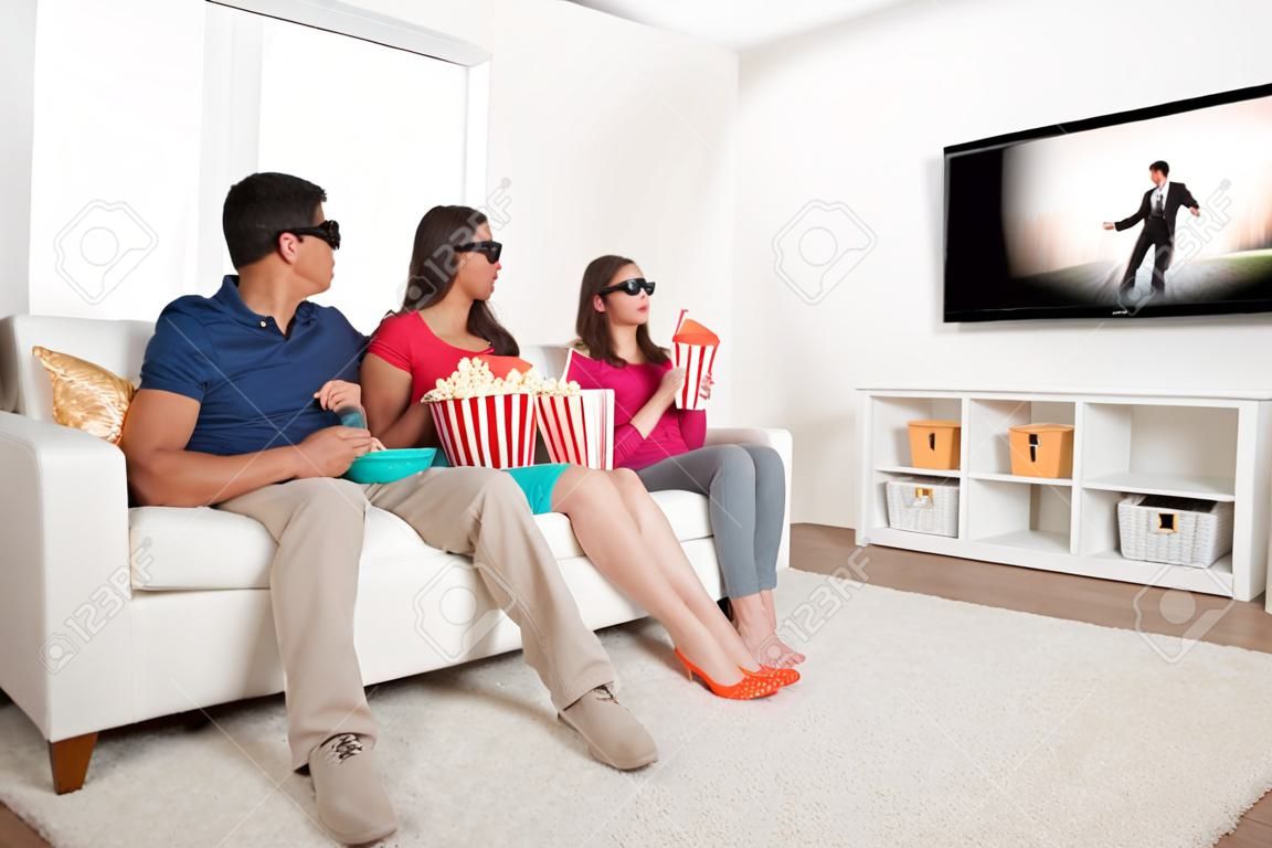 Full length of family watching 3D movie on television while having popcorn at home