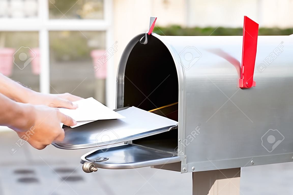 Close-up osoba umieszczająca stos listów w skrzynce pocztowej