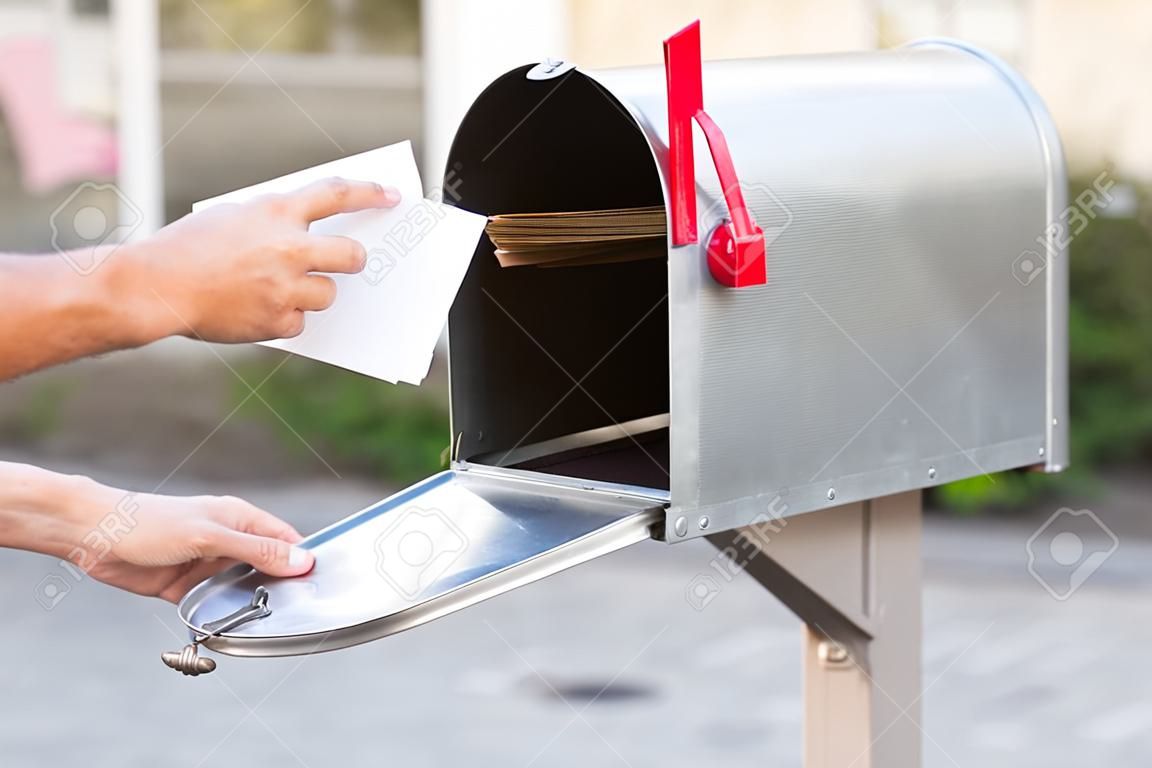 Close-up van persoon die stapel brieven in postbus stopt