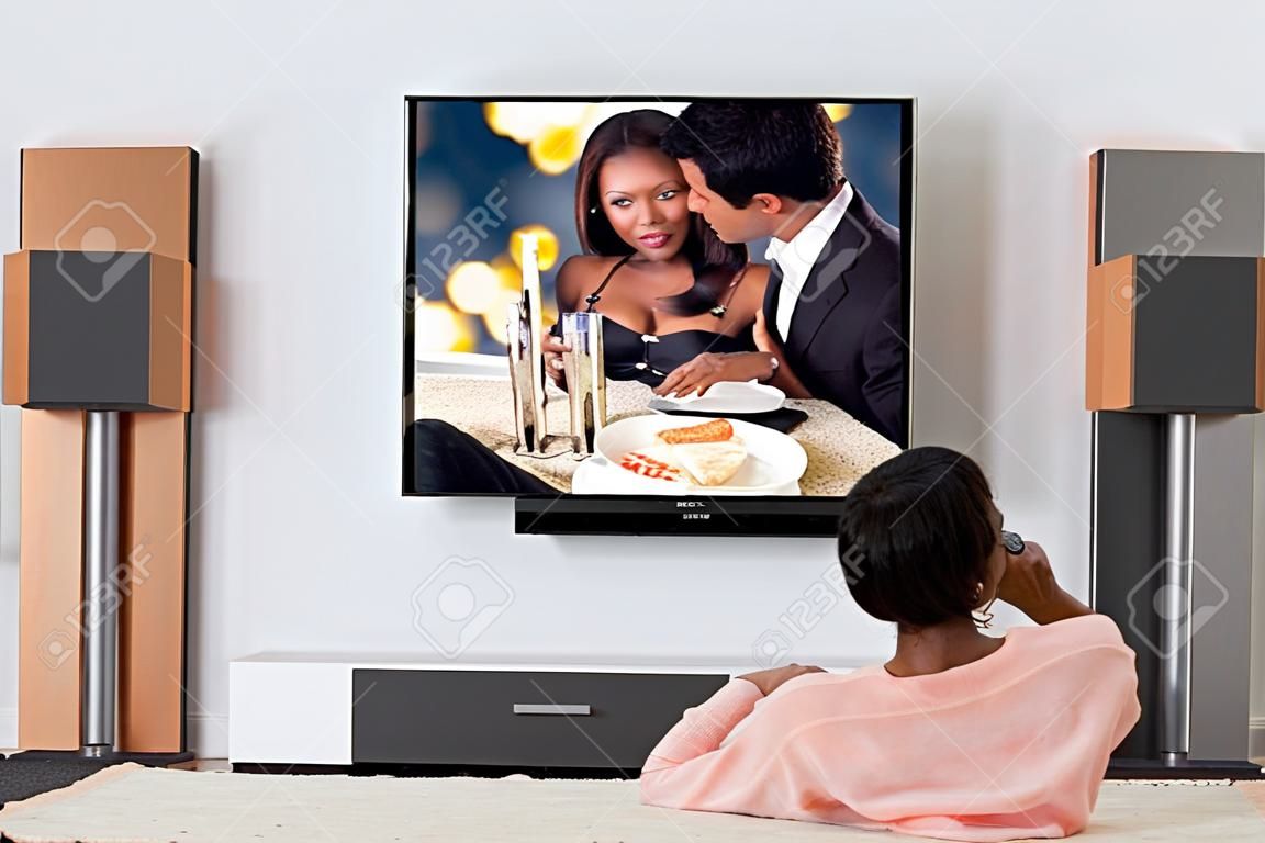 Jeune femme africaine Allongé sur le tapis de regarder la télévision