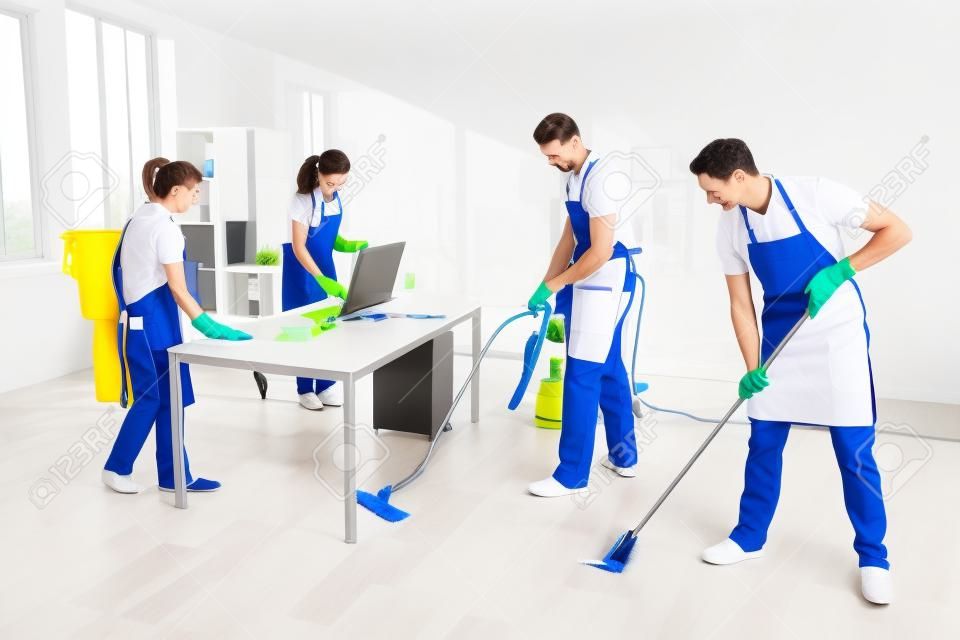 Group Of Male And Female Janitors In Uniform Cleaning The Office