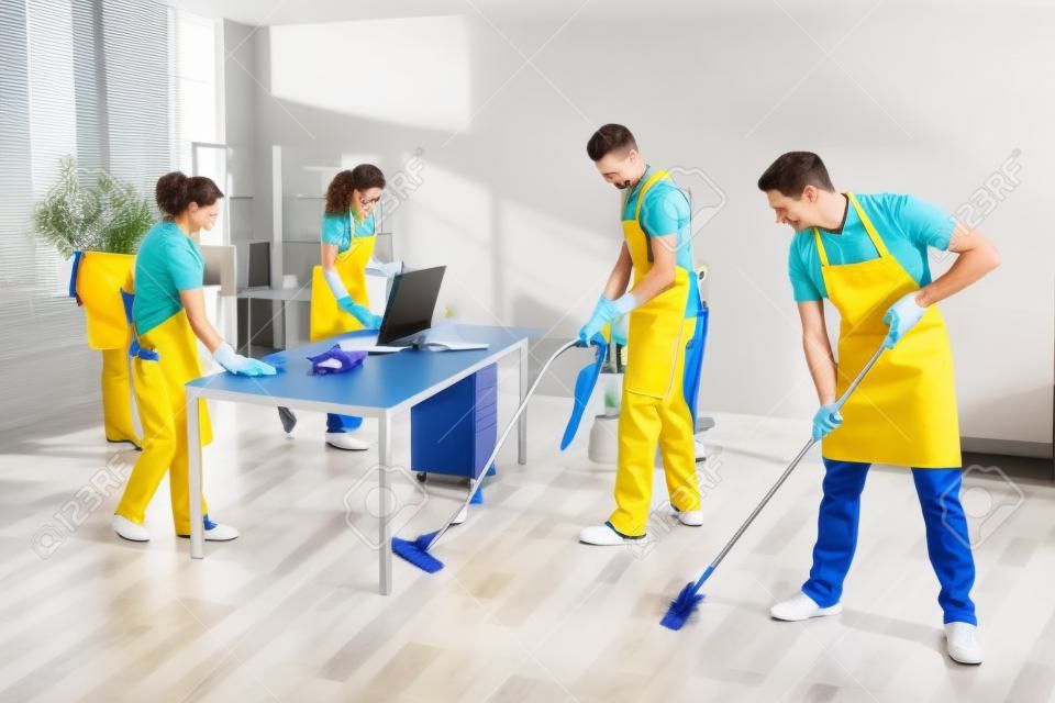 事務所を掃除する制服を着た男性と女性の管理人のグループ