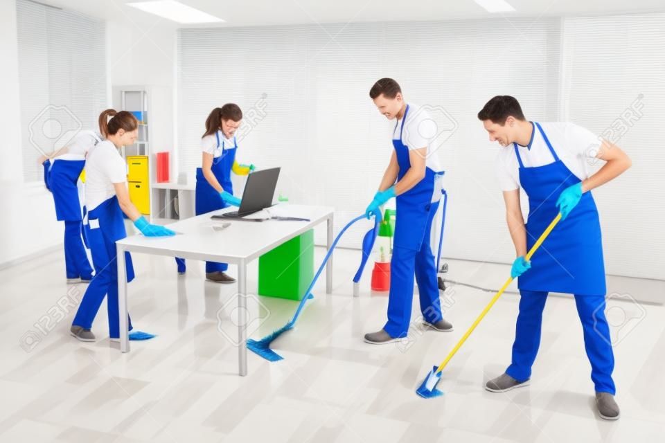 Group Of Male And Female Janitors In Uniform Cleaning The Office
