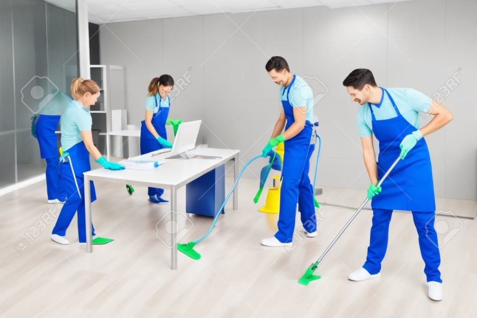 Groep mannelijke en vrouwelijke conciërges in uniform schoonmaken van het kantoor