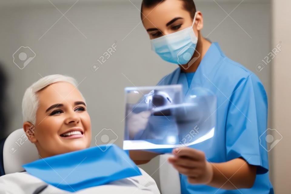 Młoda Kobieta lekarz pokazując Dental X-ray Starszy mężczyzna leczony w klinice