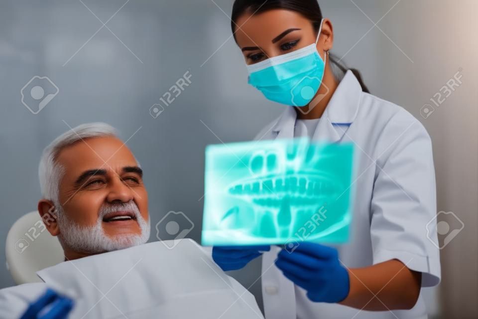 Młoda Kobieta lekarz pokazując Dental X-ray Starszy mężczyzna leczony w klinice