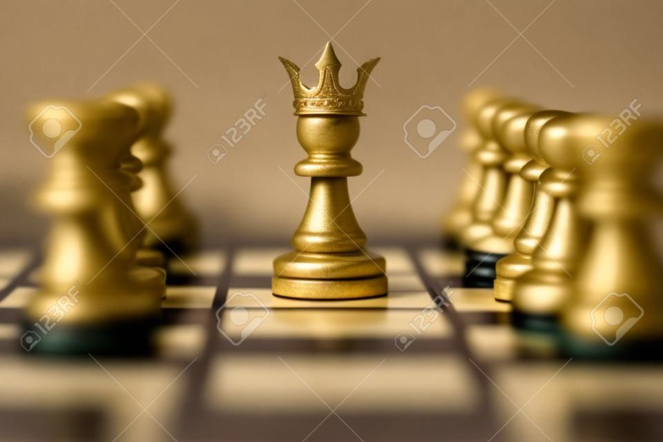 Closeup di pegno con corona re in mezzo a pezzi di scacchi a bordo gioco che rappresenta la leadership