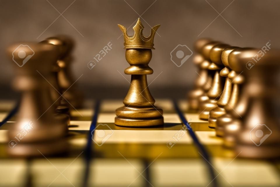 Closeup di pegno con corona re in mezzo a pezzi di scacchi a bordo gioco che rappresenta la leadership