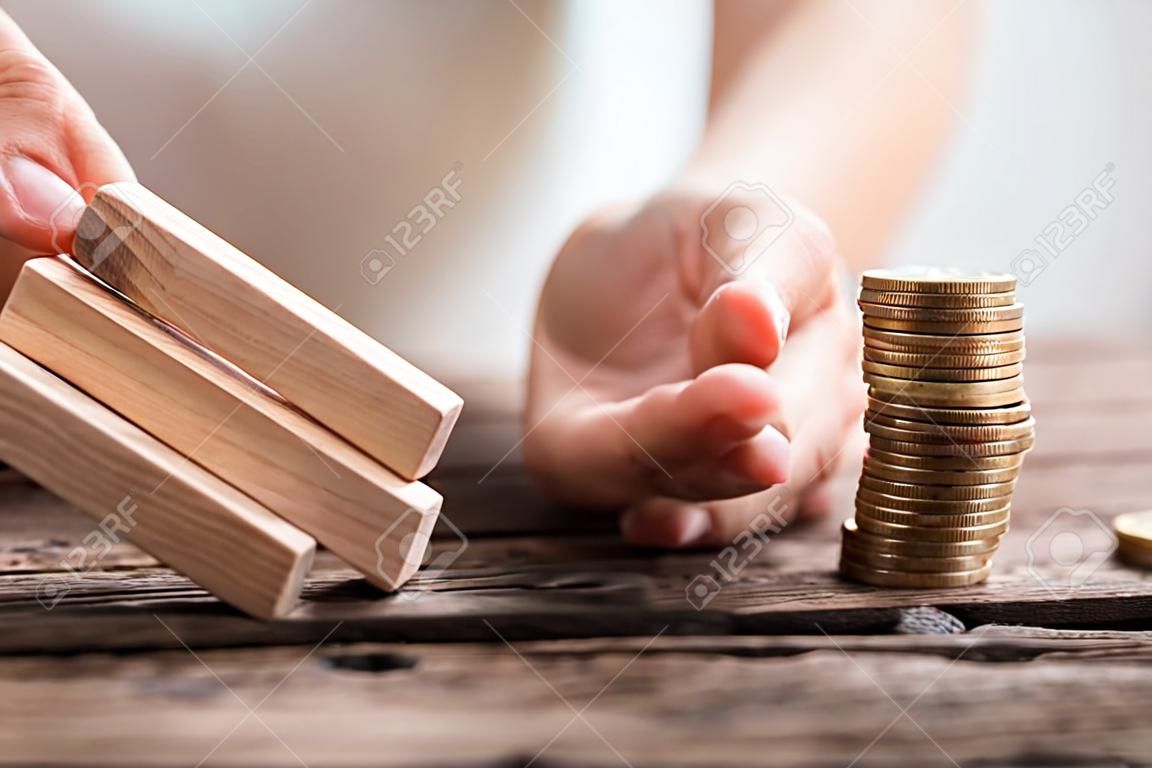 Close-up van de hand van een zakenvrouw het stoppen van de houten blokken van vallen op gestapelde munten