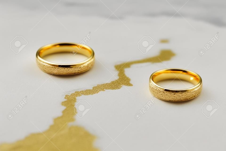 Close-up Of Two Golden Wedding Rings On Cracked Surface