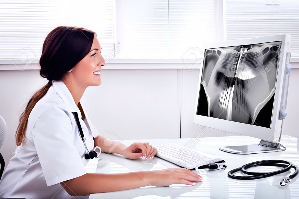 Female Doctor Looking At Teeth X-ray On Computer Over Desk In Clinic