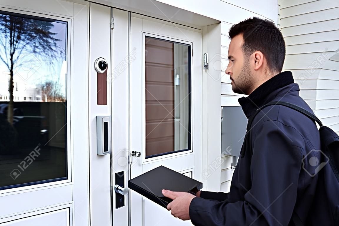 Hombre de pie a la entrada de la casa presionando el timbre de la puerta