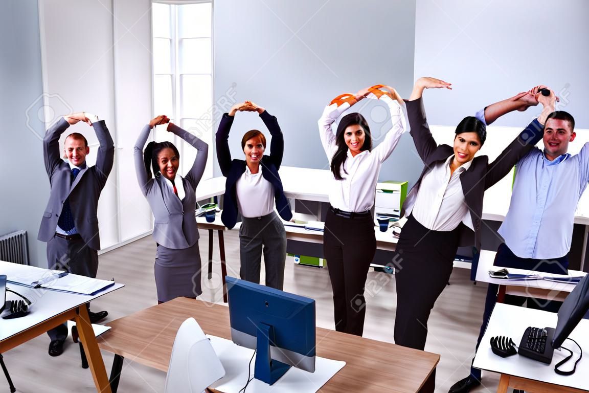 Gruppe lächelnder multiethnischer Geschäftsleute, die Dehnübungen am Arbeitsplatz machen