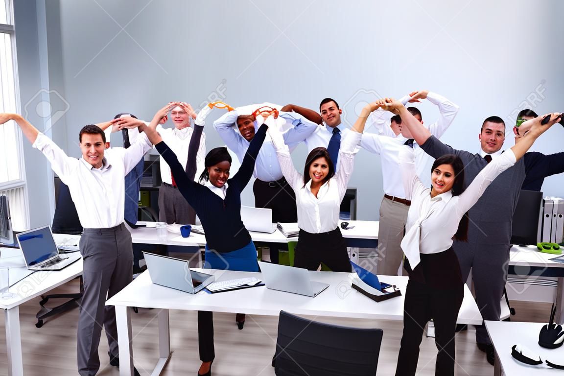 Groupe d'hommes d'affaires multiethniques souriants faisant des exercices d'étirement sur le lieu de travail
