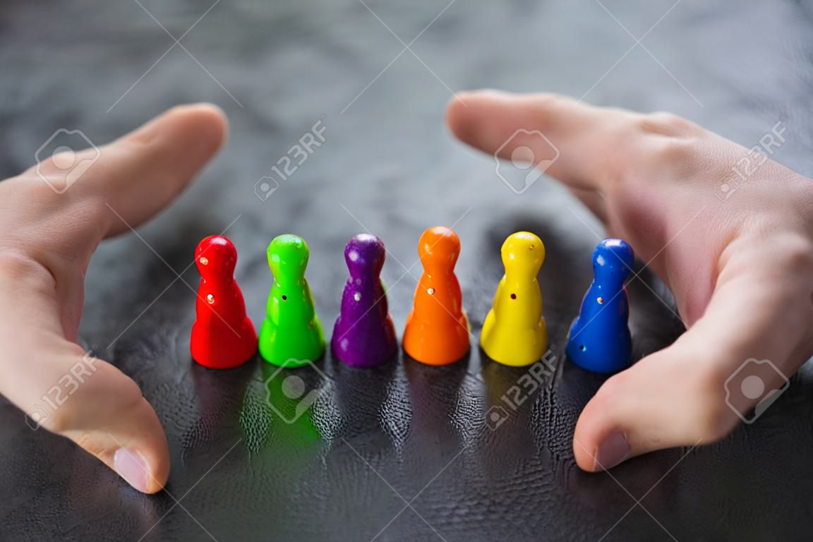 Primo piano della mano di una persona che protegge le pedine multicolori che formano un cerchio sopra la scrivania bianca