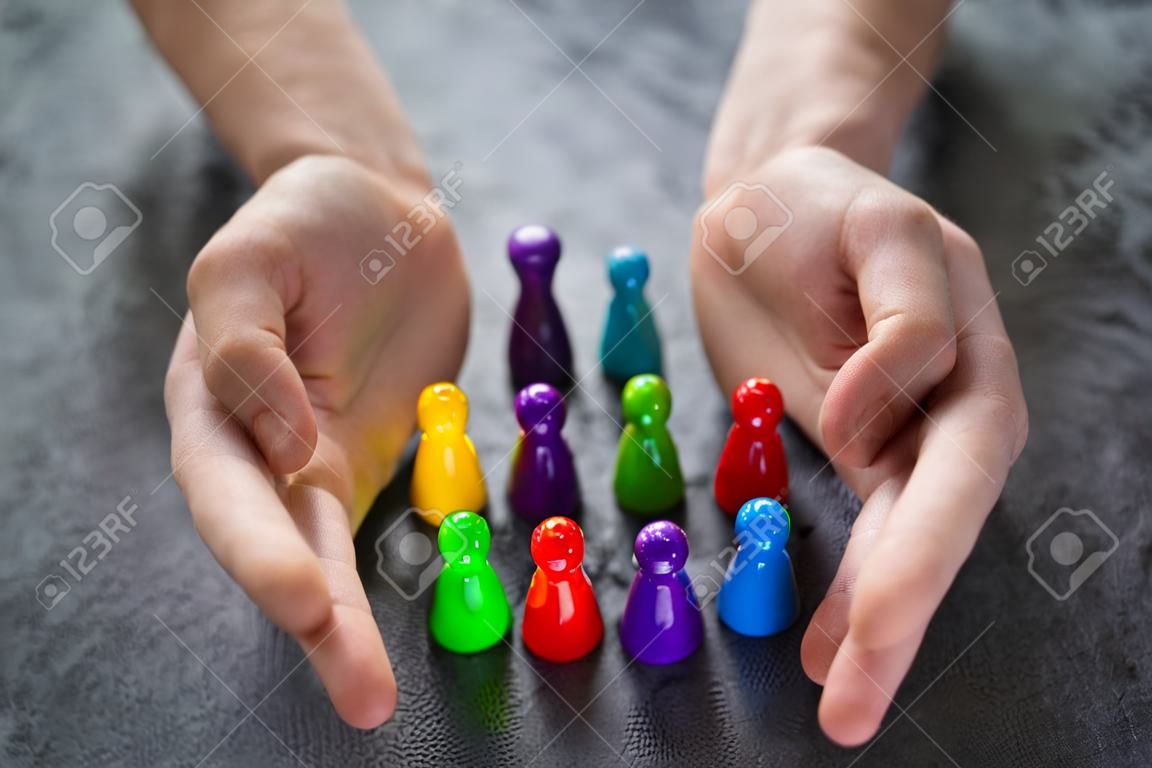 Primo piano della mano di una persona che protegge le pedine multicolori che formano un cerchio sopra la scrivania bianca