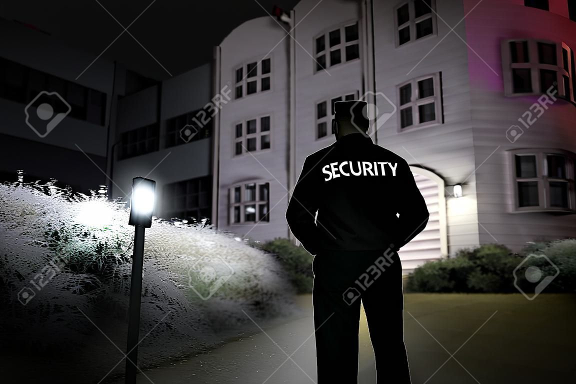 Guardia de seguridad caminar perímetro del edificio con linterna en la noche