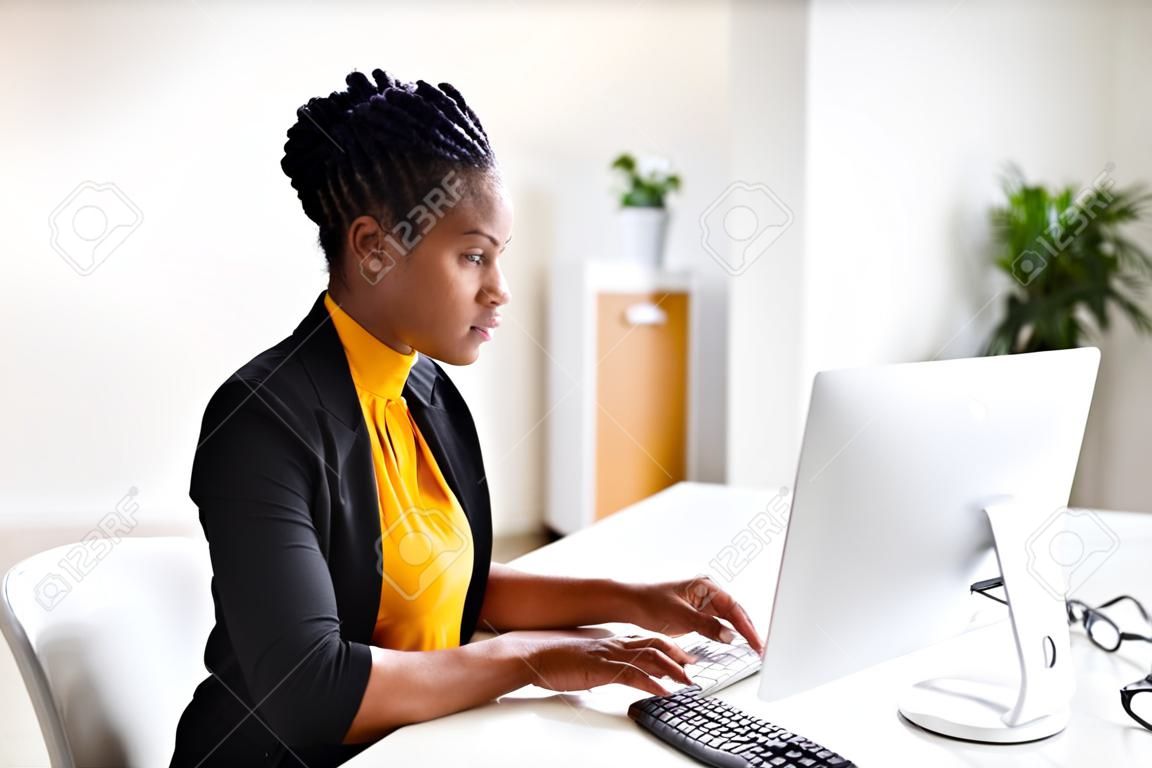 Afrykańska kobieta wypełnia ankietę lub formularz na komputerze stacjonarnym