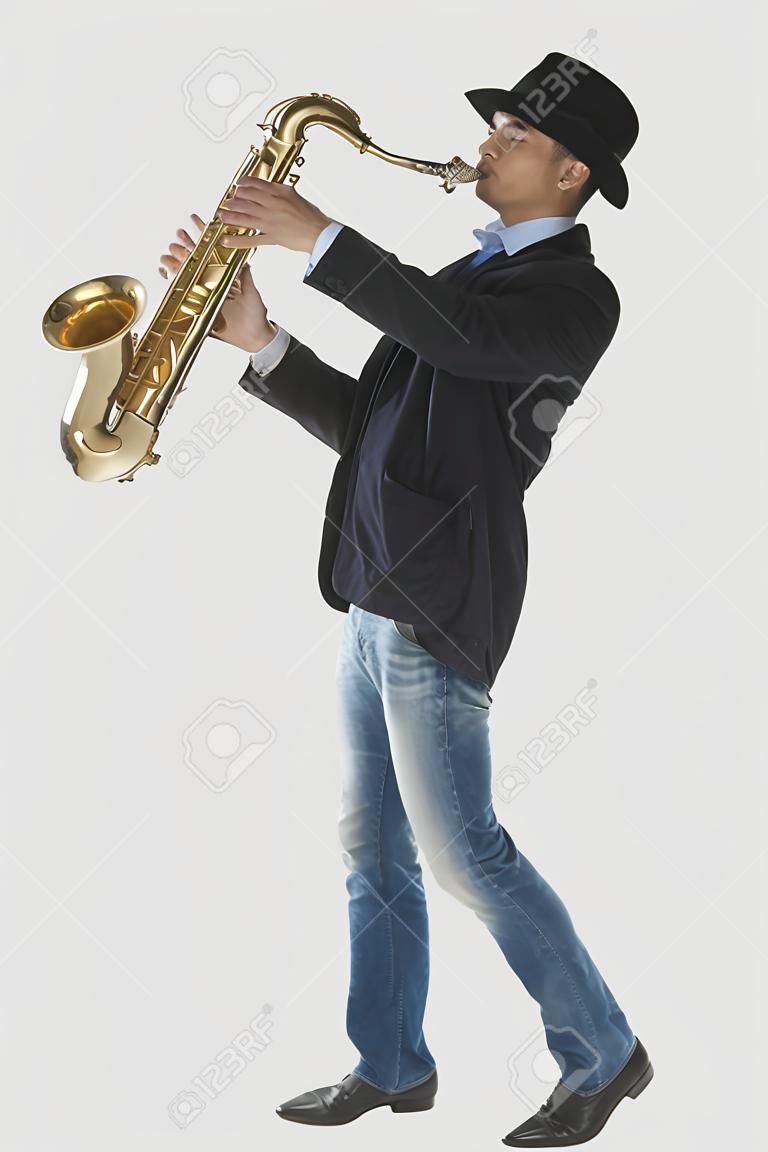 Pełnej długości Portret mężczyzny gra na saksofon samodzielnie na tle