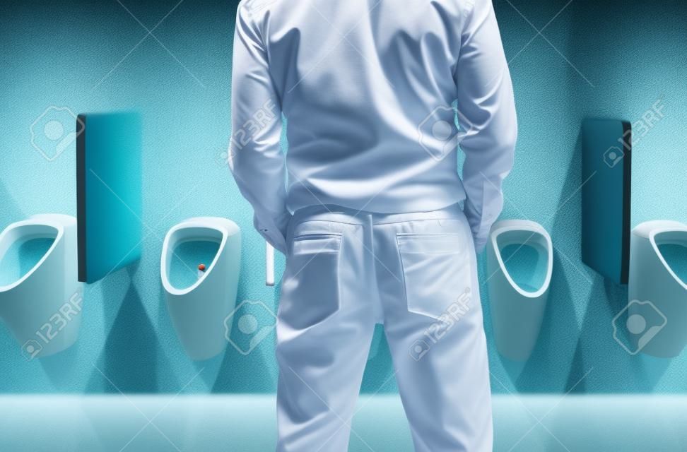 Mężczyzna stojący siusia do pisuaru w toalecie lub koncepcji nietrzymania moczu