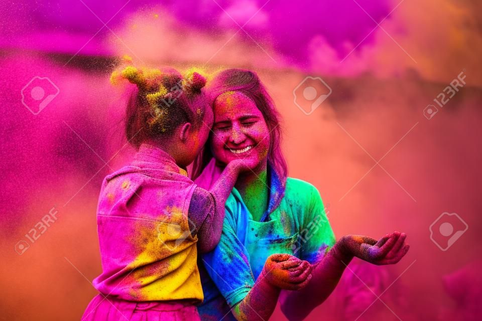 mother and daughter are played on the nature of the colors. two playing with the color in holi festival