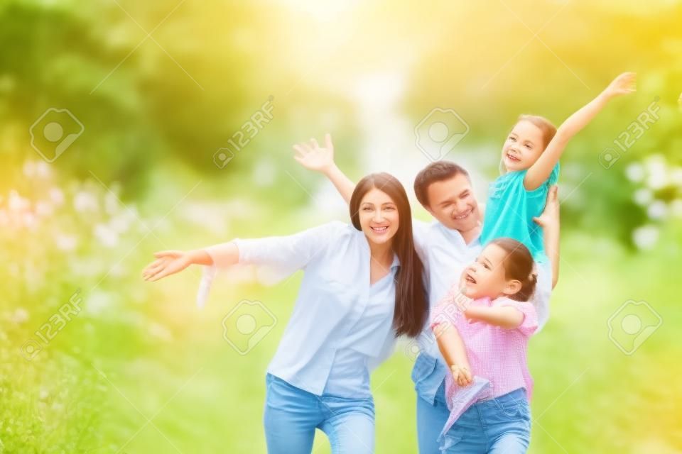 Glückliche Familie auf Sommerspaziergang, Mutter, Vater und Töchter, die im Park spazieren und die schöne Natur genießen.