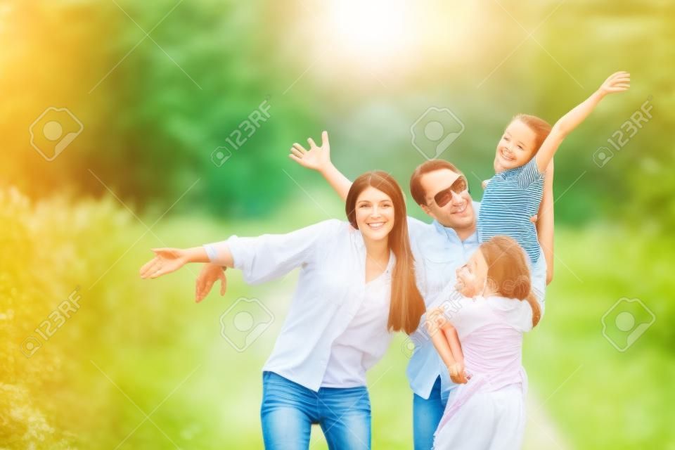 Família feliz na caminhada do verão, mãe, pai e filhas que andam no parque e apreciam a natureza bonita.