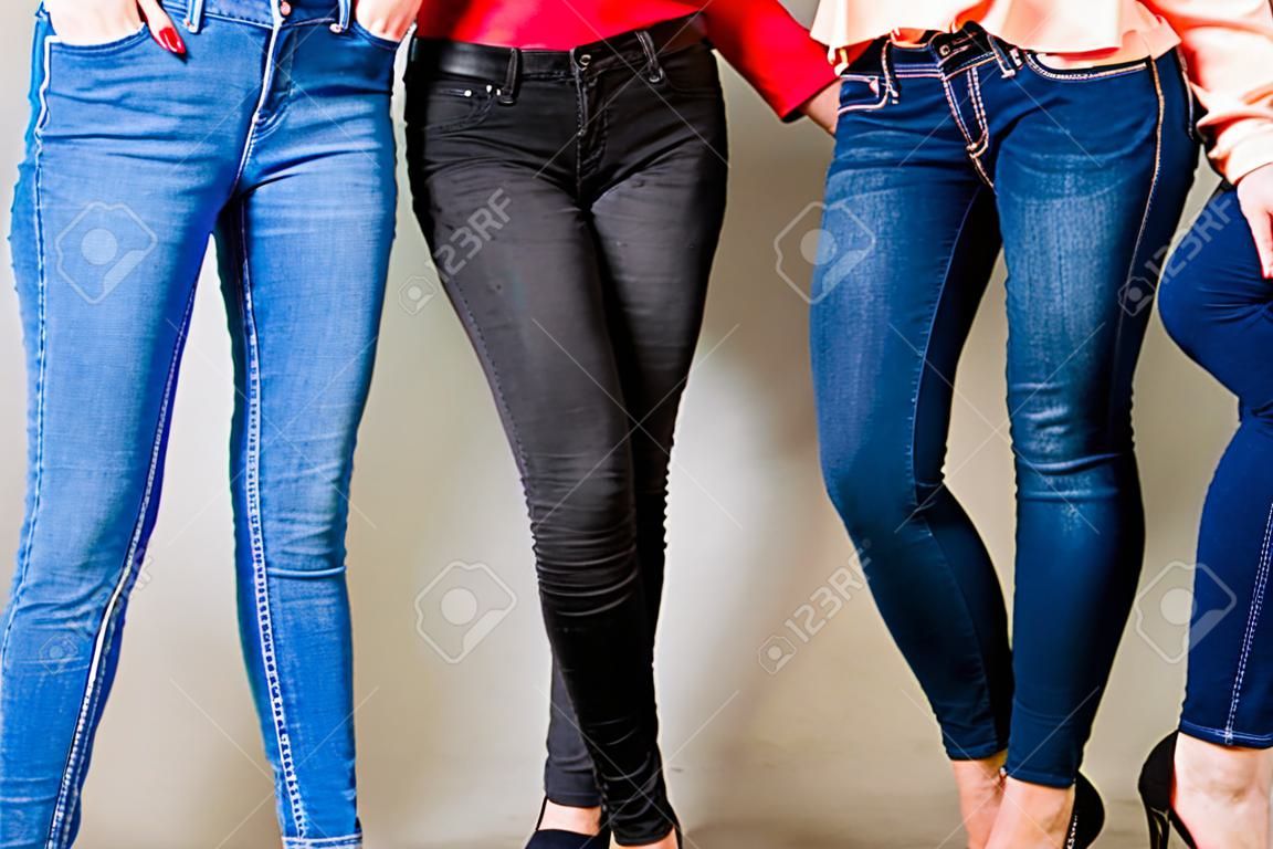 Three woman wearing different colors of trousers. Black, blue and navy skinny slim jeans showing body curves.